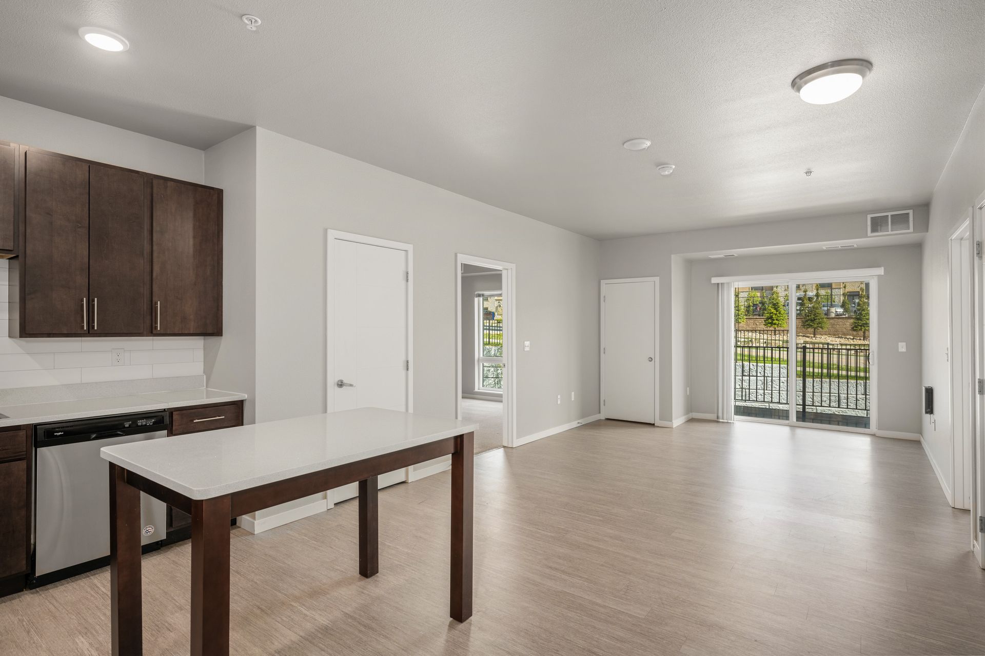 Modern apartment interior with kitchen, island, and sliding glass door to balcony.