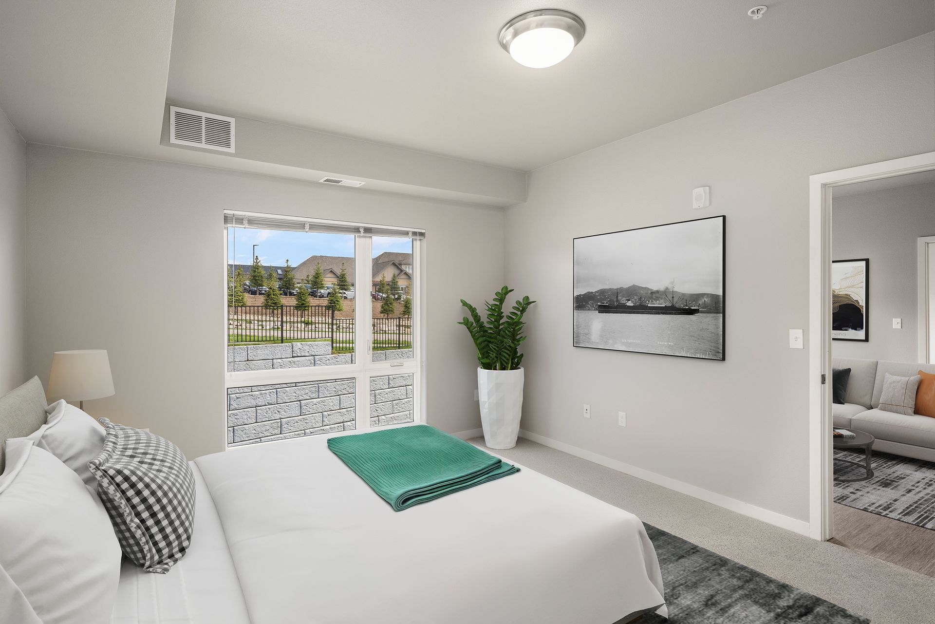 Bedroom with a bed, large window, and open doorway to a living area.