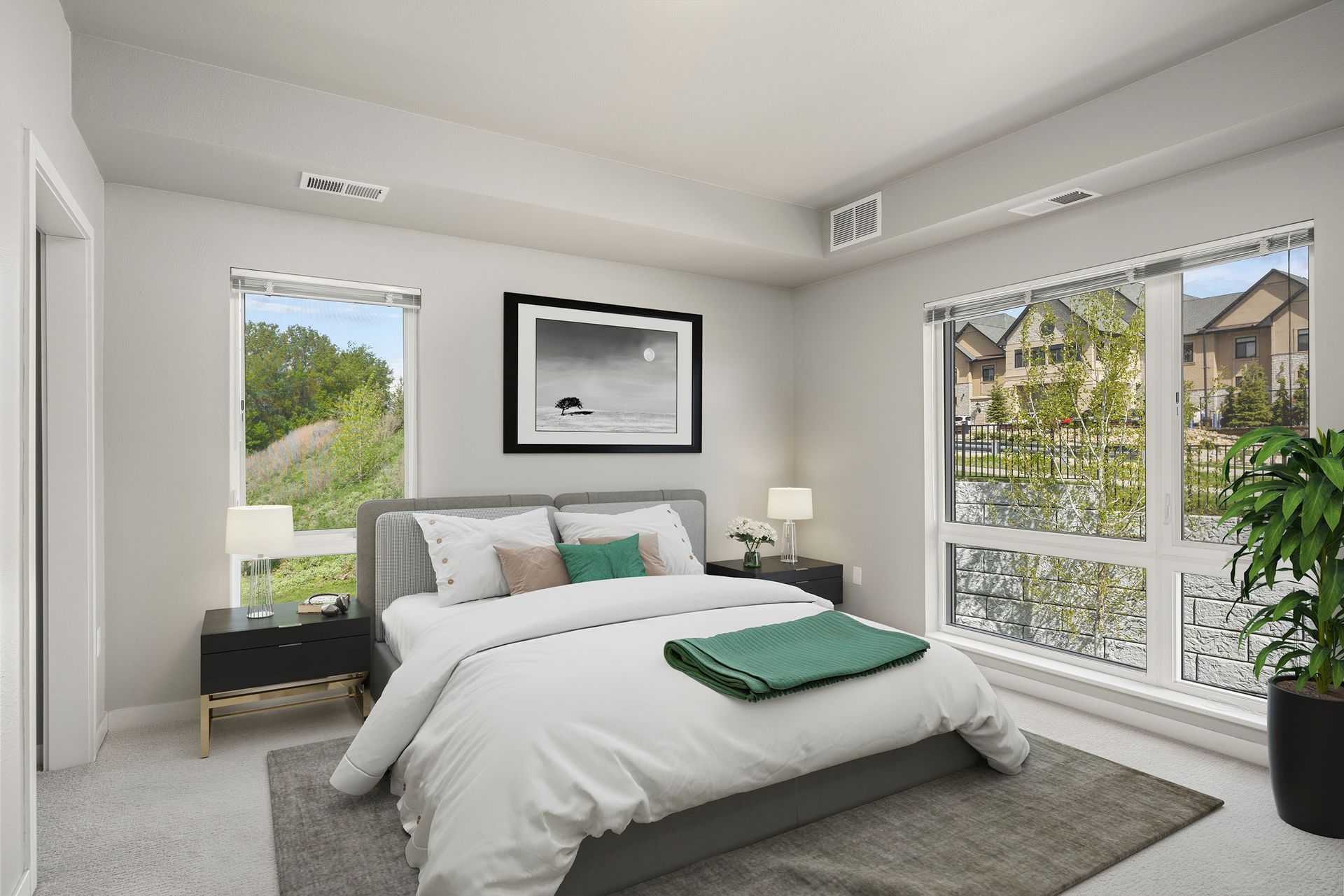Bedroom with bed, windows, artwork, and nightstands. Neutral tones.