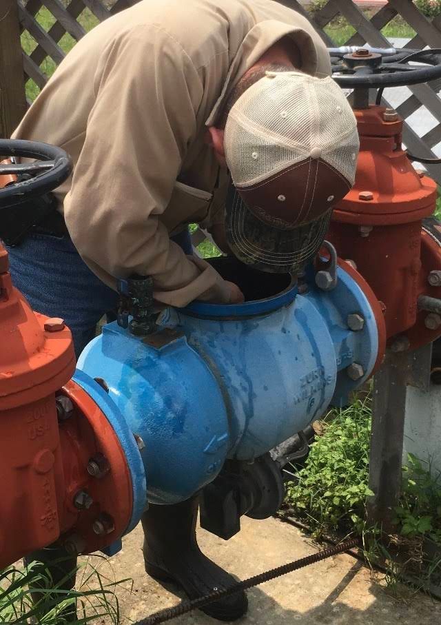 A man is looking into a blue pipe.