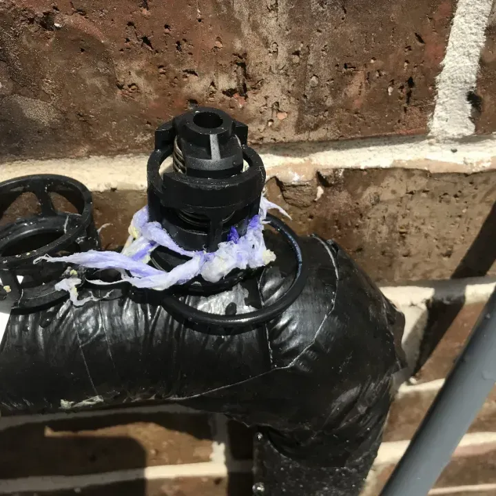 A black pipe is attached to a brick wall