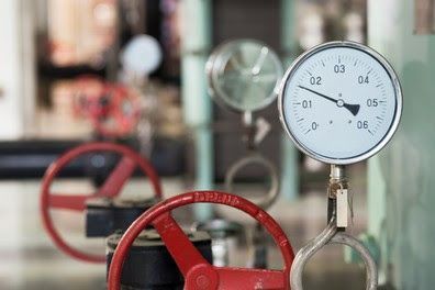 A close up of a pressure gauge on a pipe in a factory.