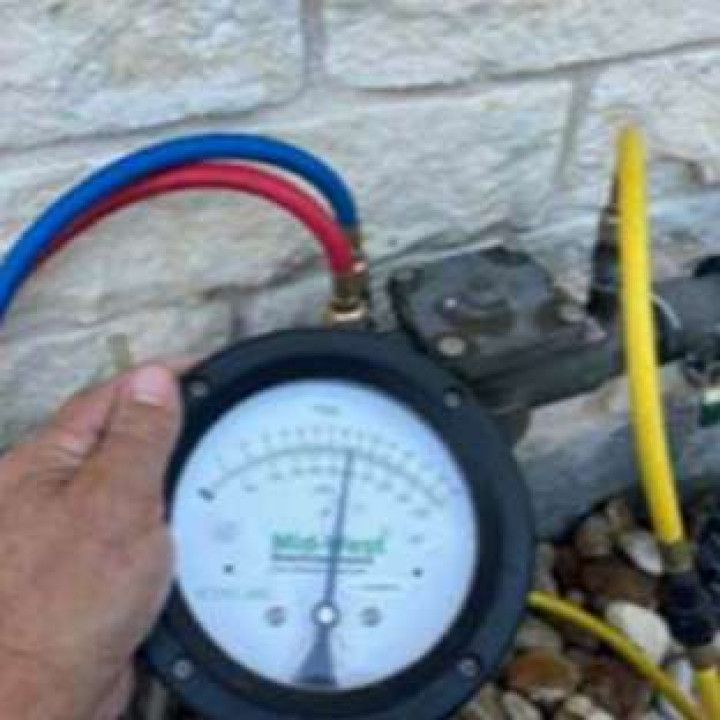 A person is holding a pressure gauge next to a hose.