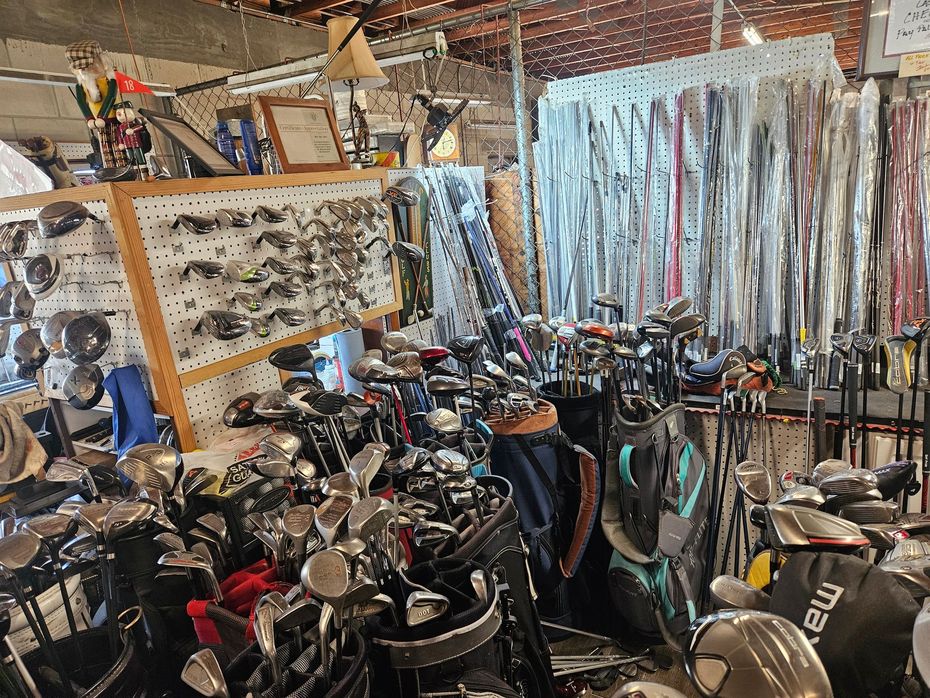 Cluttered golf shop with rows of golf clubs, bags, and accessories packed tightly together