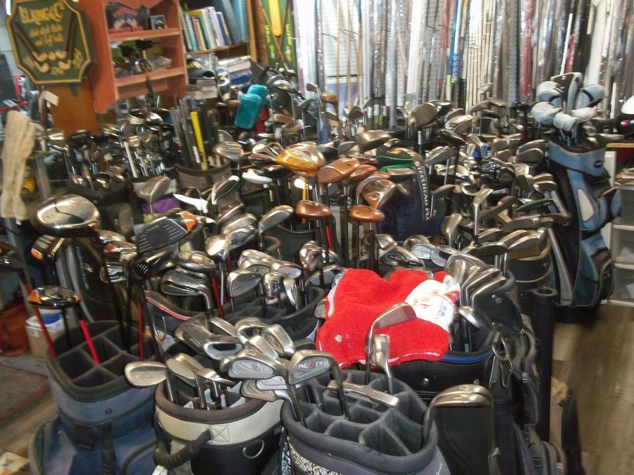 A cluttered golf shop store interior filled with numerous bags of assorted golf clubs.
