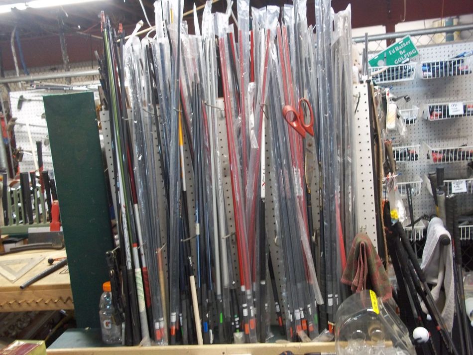 A large assortment of fishing rods in plastic sleeves displayed on a pegboard rack in a store.