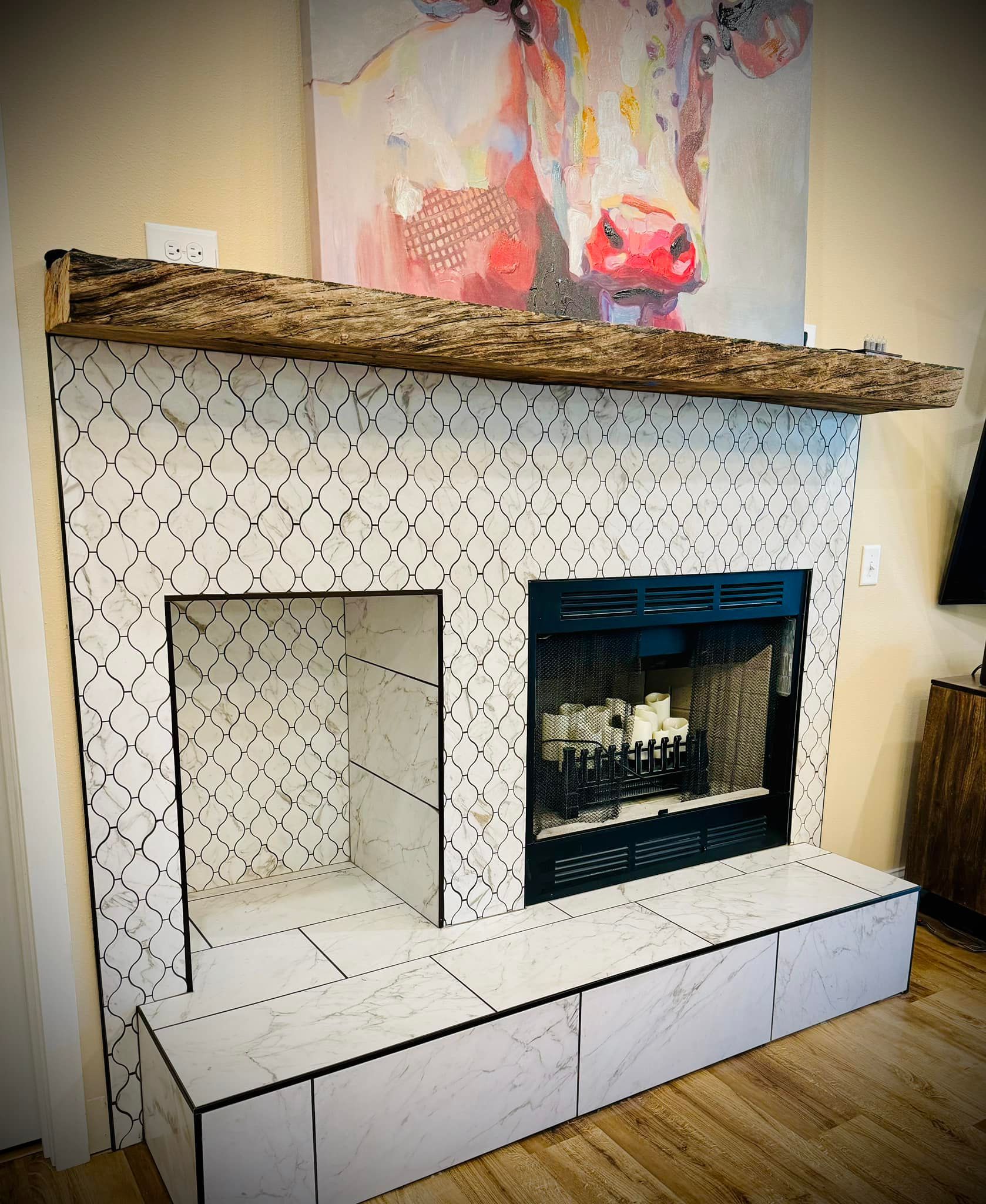 Fireplace with white tile, wooden mantle, and a cow painting.