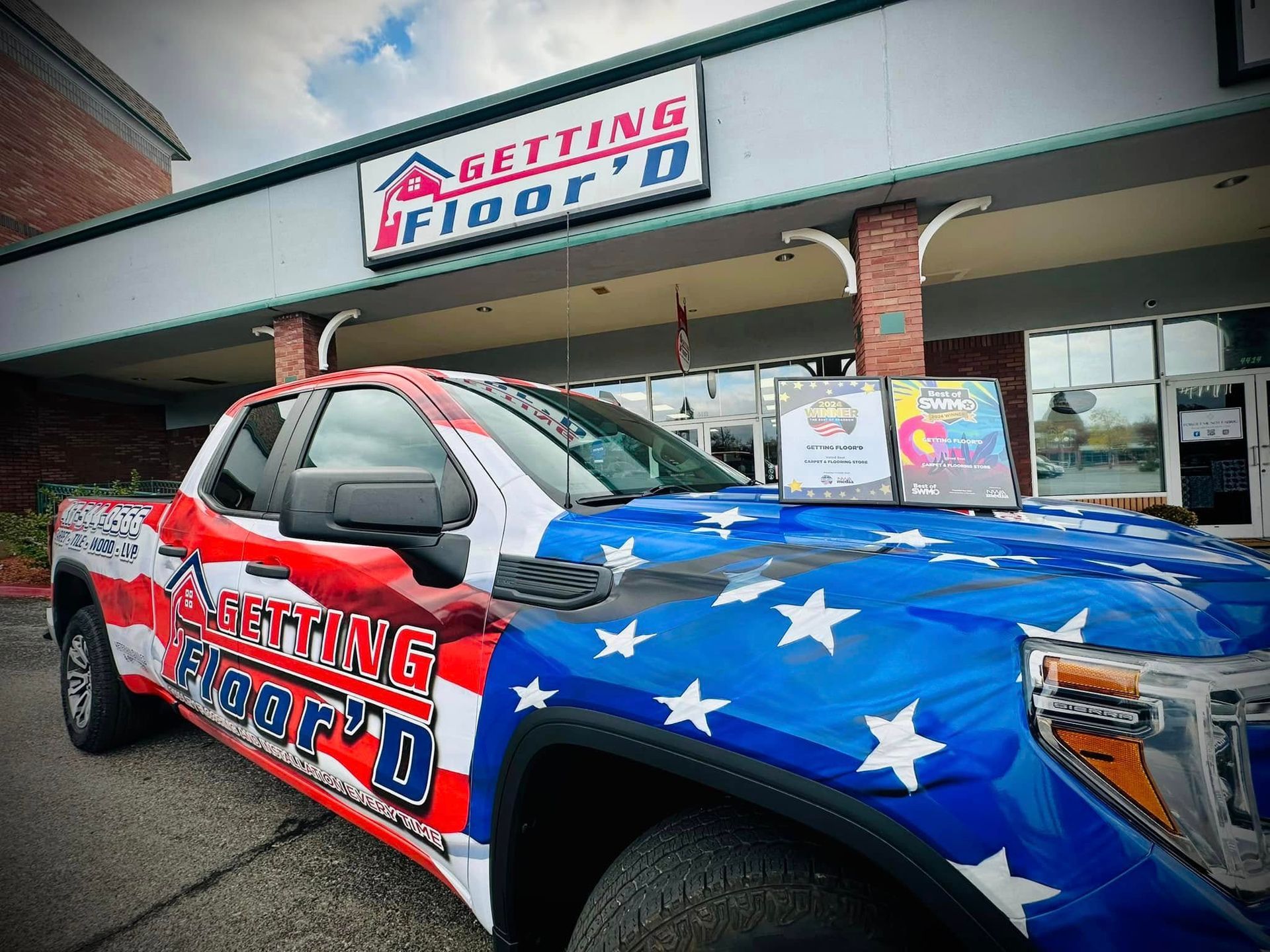 A truck with an American flag wrap parked in front of