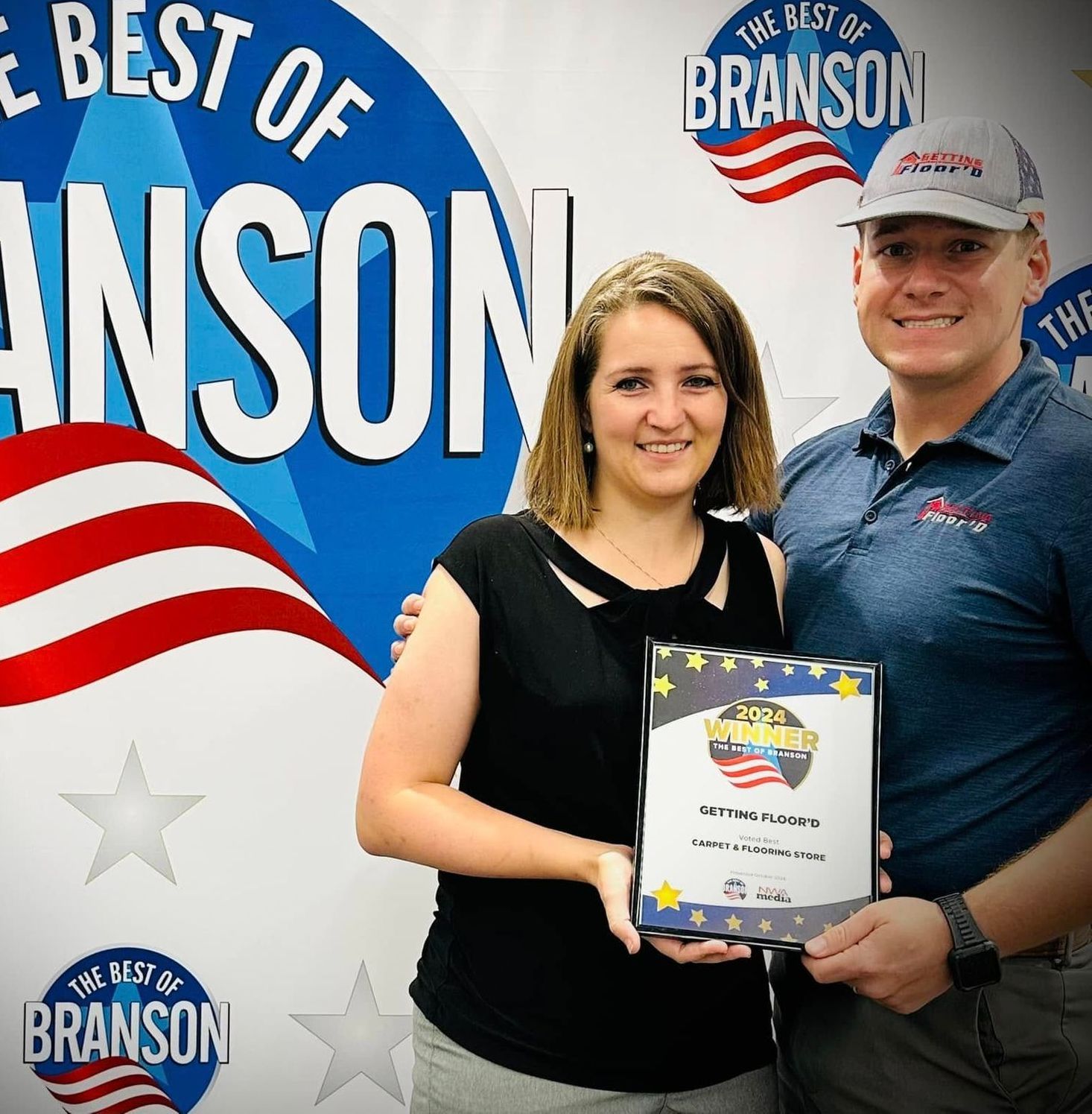 Two people holding an award, smiling in front of a