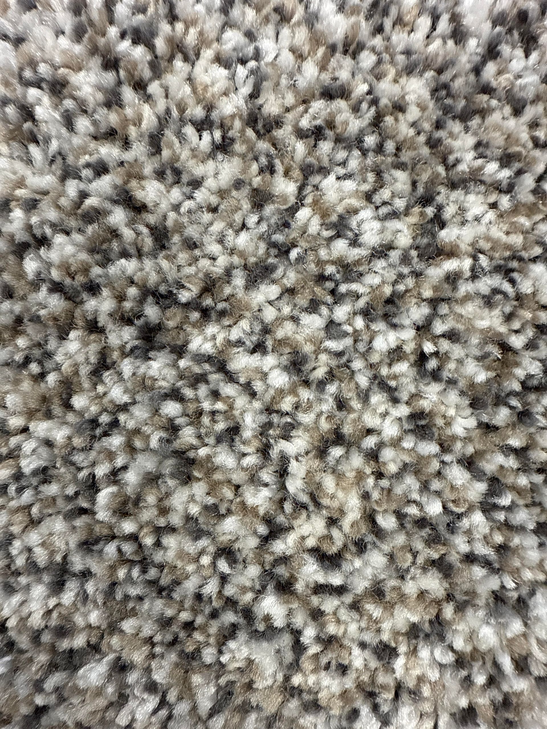 Close-up of speckled beige and gray carpet with a shaggy, textured pile.