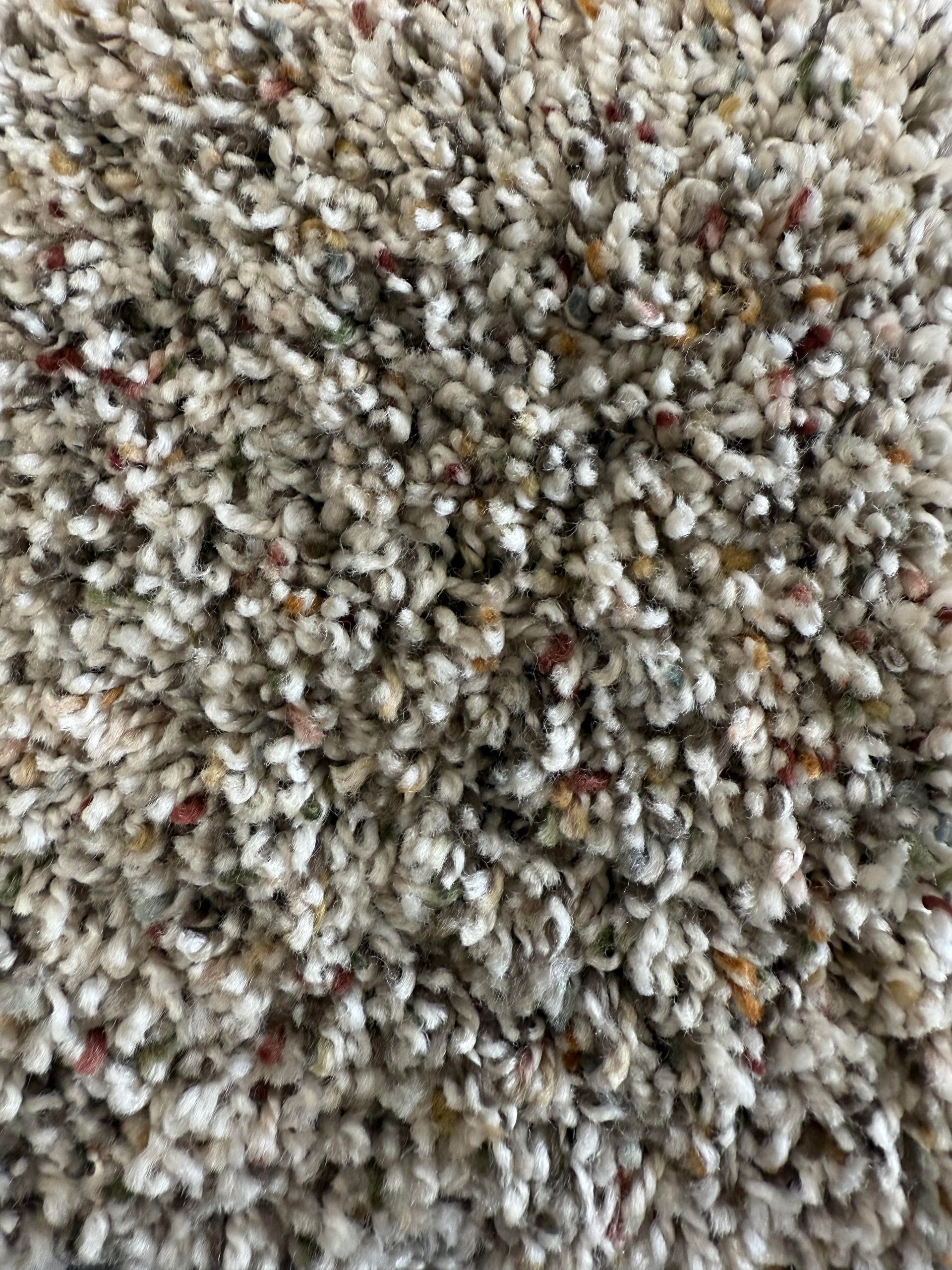 Close-up of a textured beige and brown carpet with flecks of red and gold.