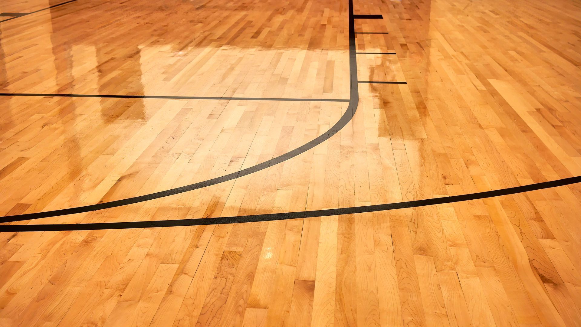 A basketball court with a wooden floor and black lines.