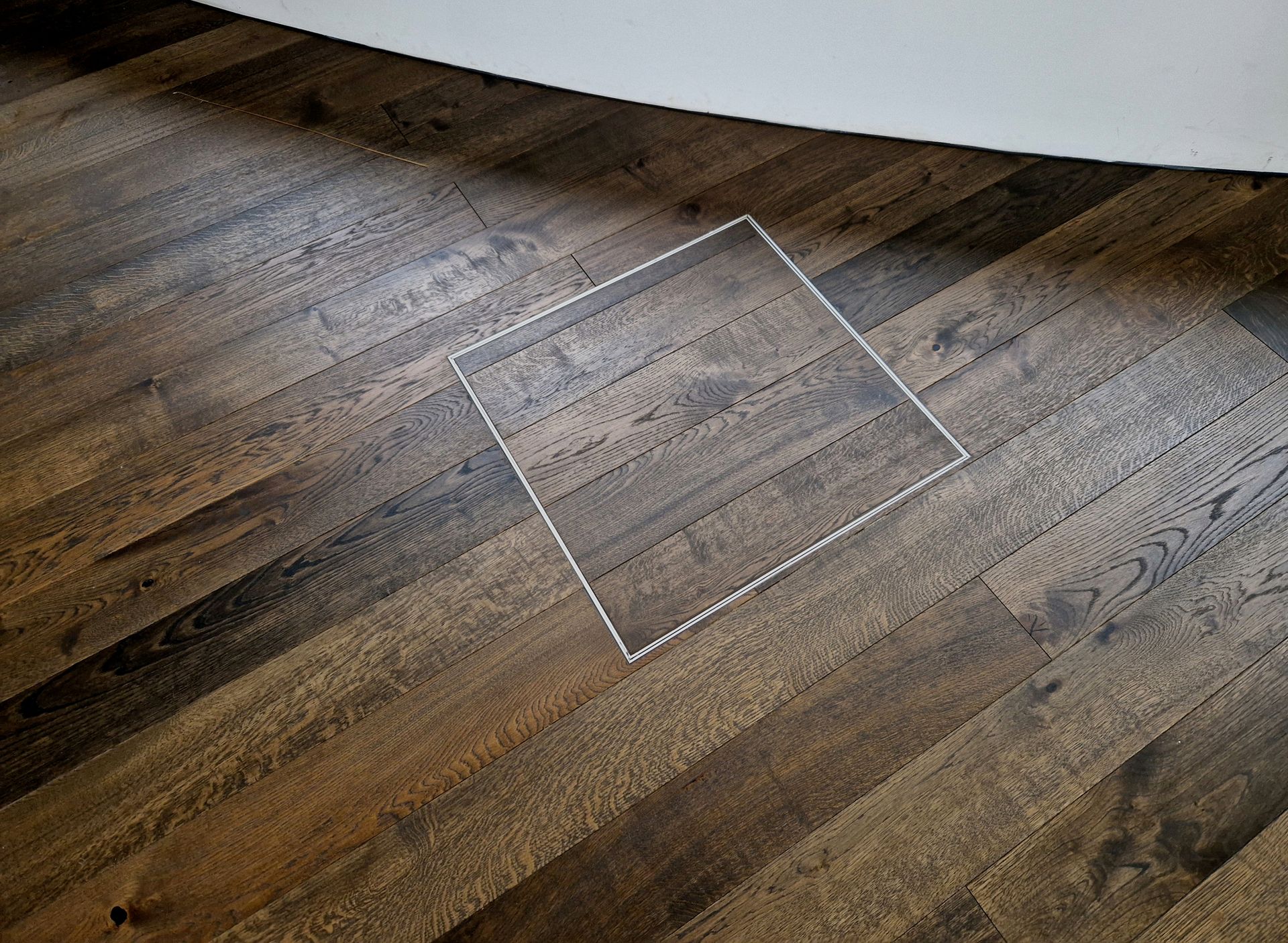 A wooden floor with a square hole in it.
