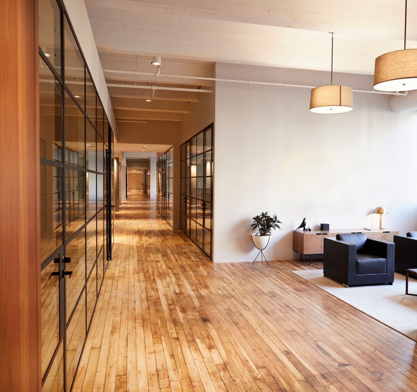 A long hallway with hardwood floors and glass walls