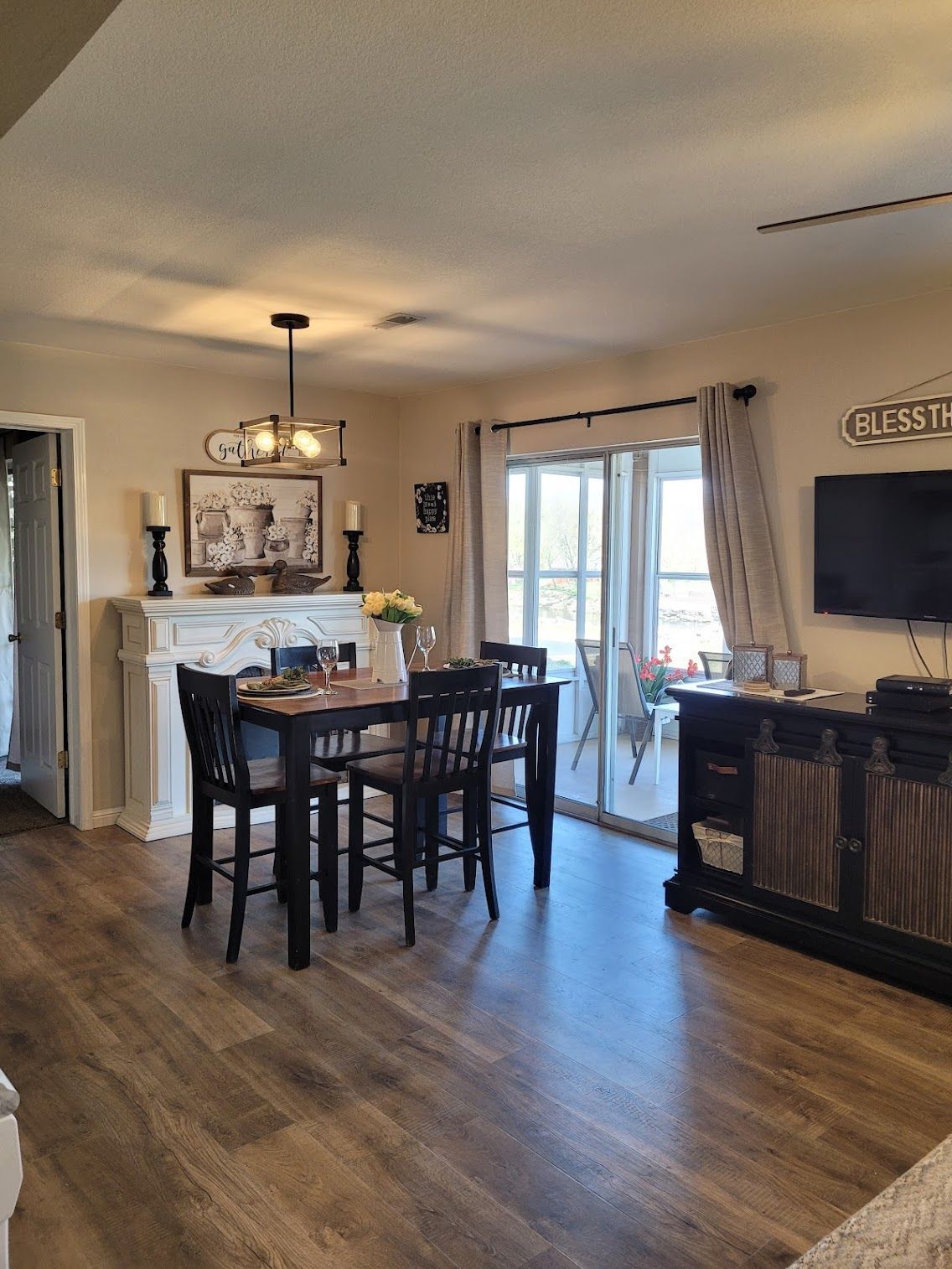 Dining area with table, chairs, fireplace, sliding doors, and a TV on a cabinet.