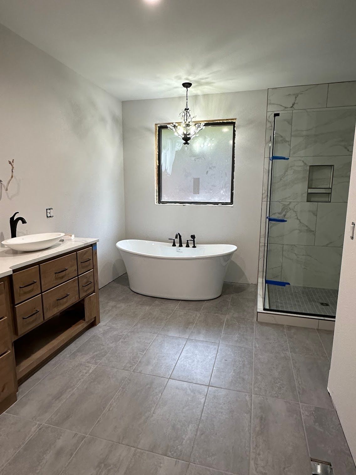 Bathroom with tub, shower, and vanity with gray tile floor and neutral walls.