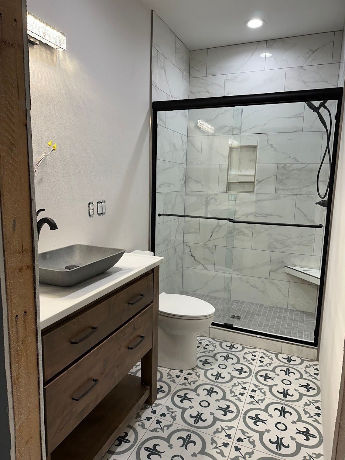 Modern bathroom with patterned tile floor, shower, and vanity.