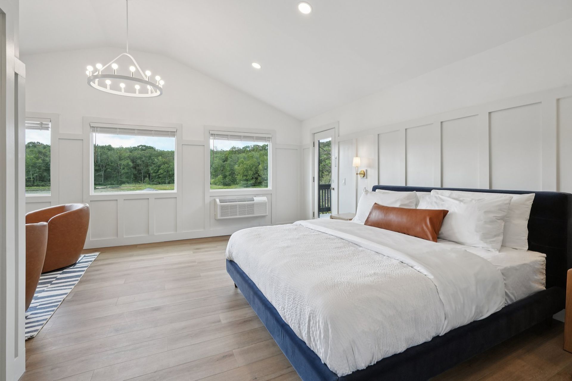 Bright bedroom with a large bed, windows overlooking a lake, and neutral colors.