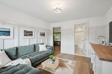 Cozy living room with a teal sectional sofa, wooden floors, and white paneling.