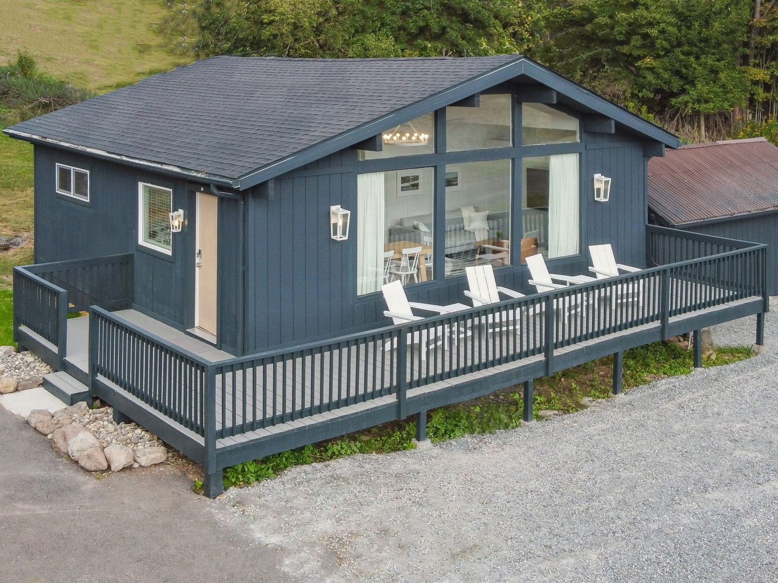 Blue cabin with deck and white chairs.