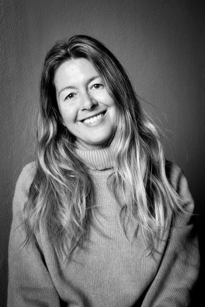 Donna con lunghi capelli lisci , indossa un maglioncino a collo alto, sorridente, in bianco e nero.