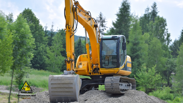 A yellow excavator is sitting on top of a pile of gravel.