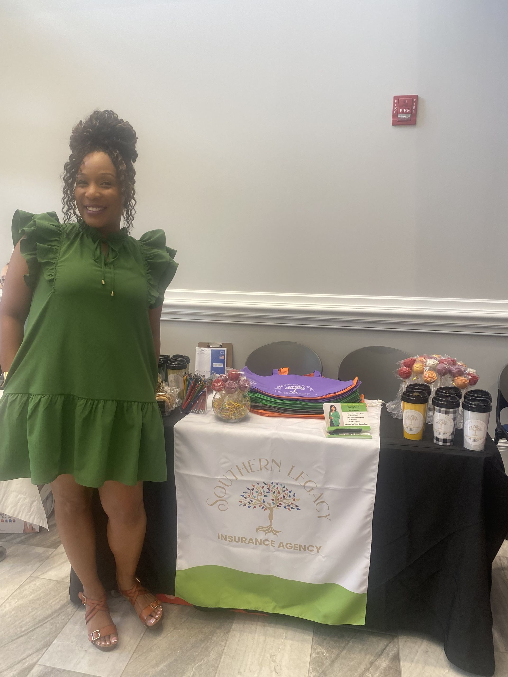 A woman in a green dress is standing in front of a table.
