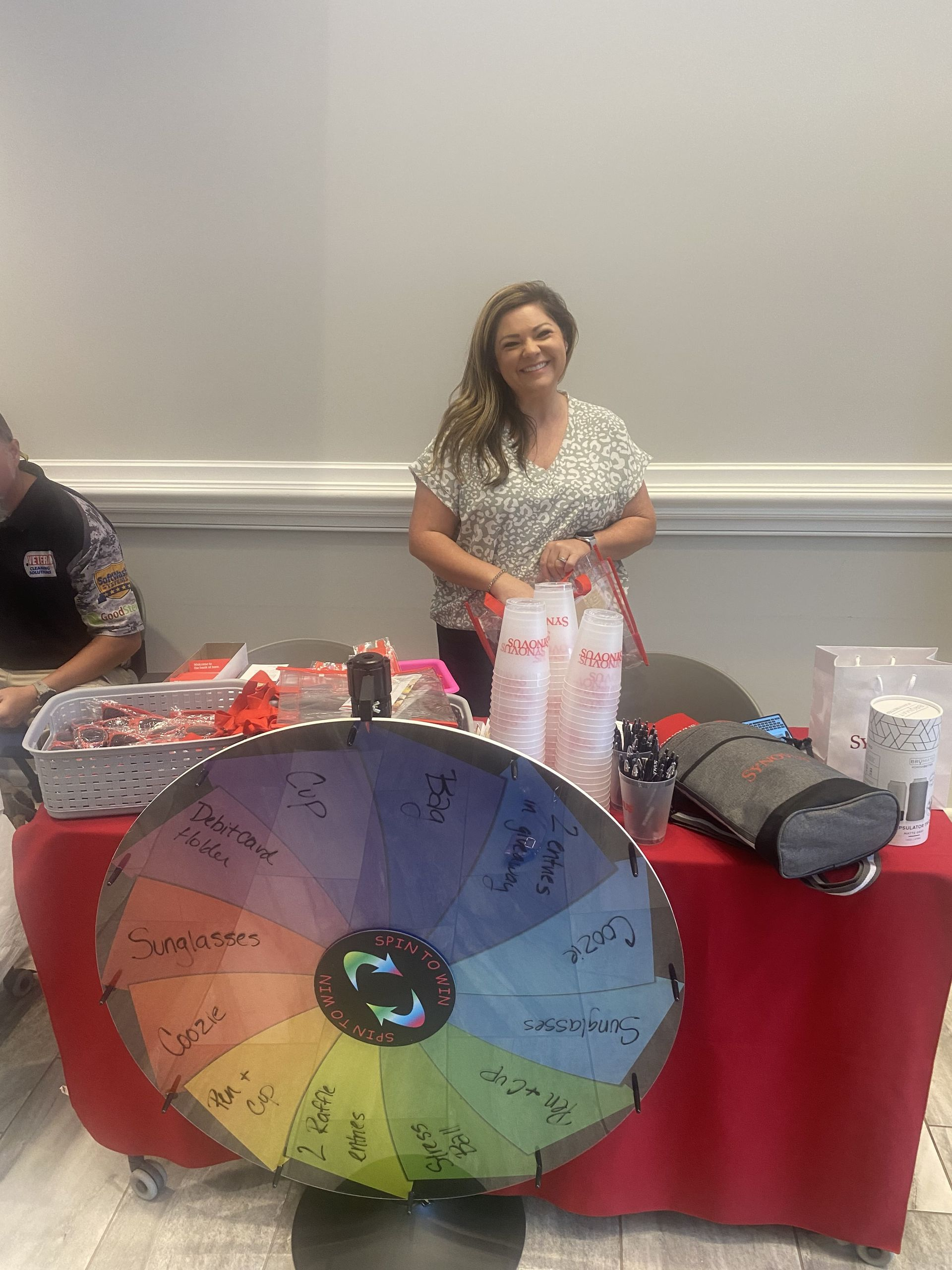 A woman is standing in front of a spinning wheel at a table.
