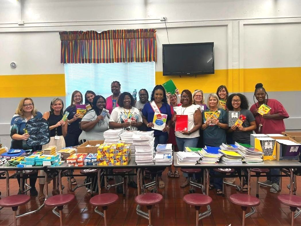A group of people are standing around a table holding books.