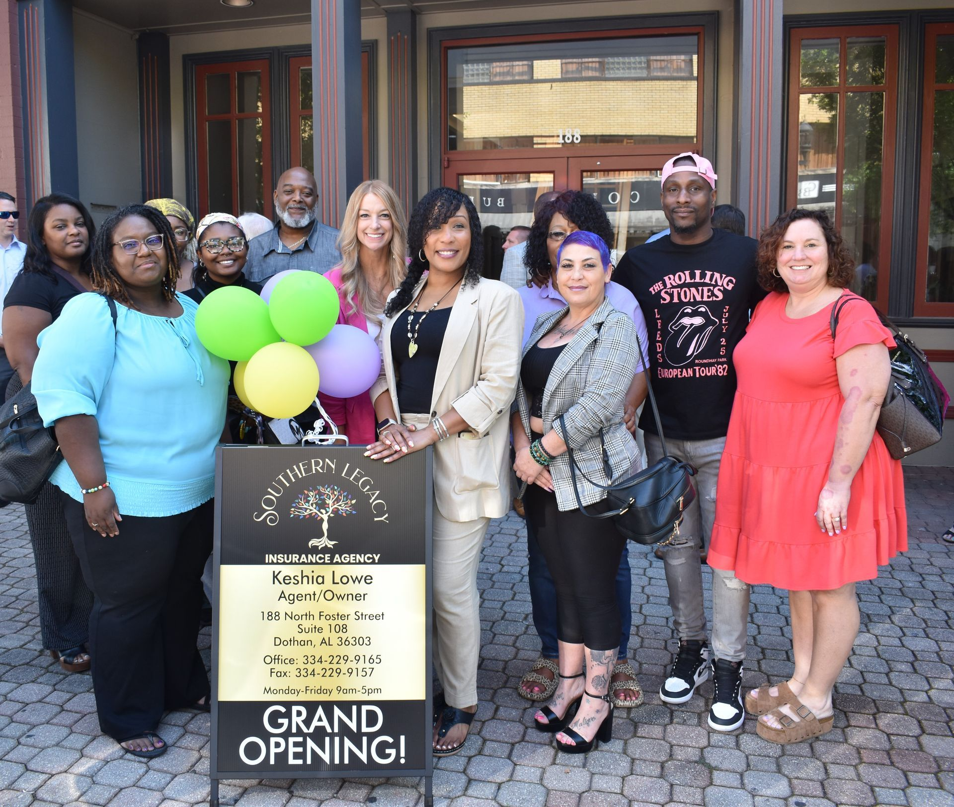 A group of people standing in front of a sign that says grand opening.