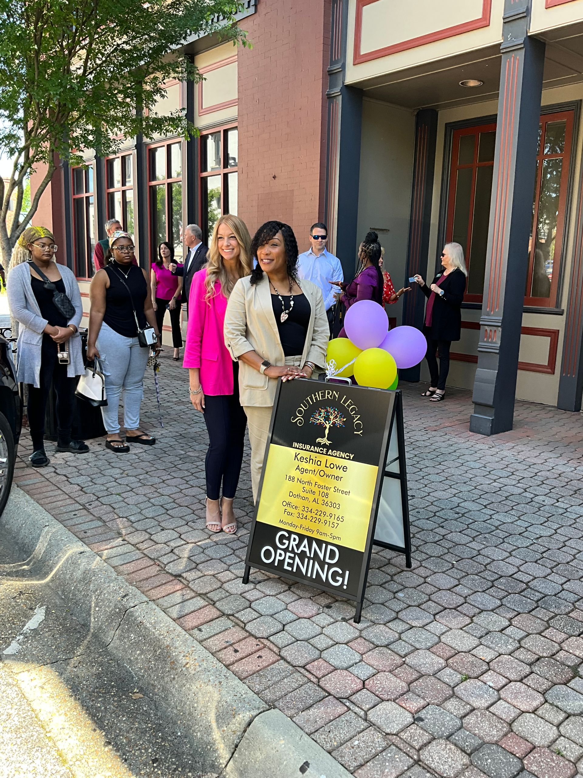 Two women are standing next to a sign that says `` grand opening ''.