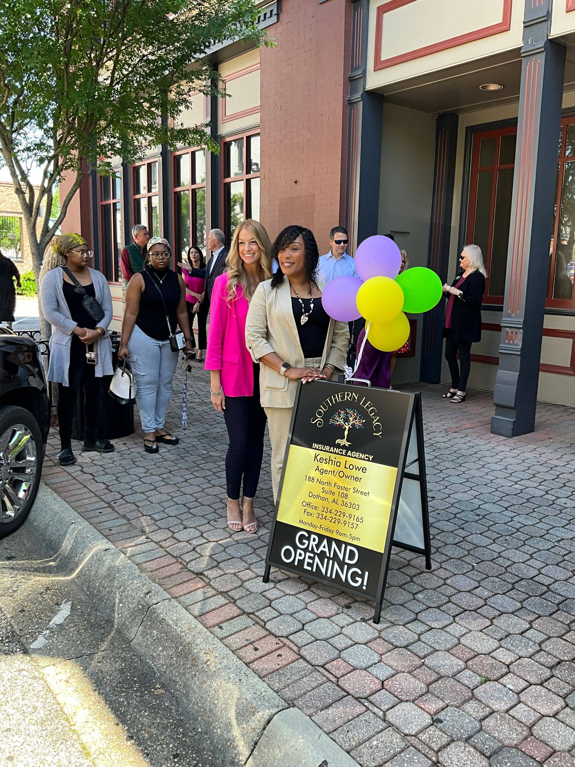 A group of people are standing in front of a building holding balloons.