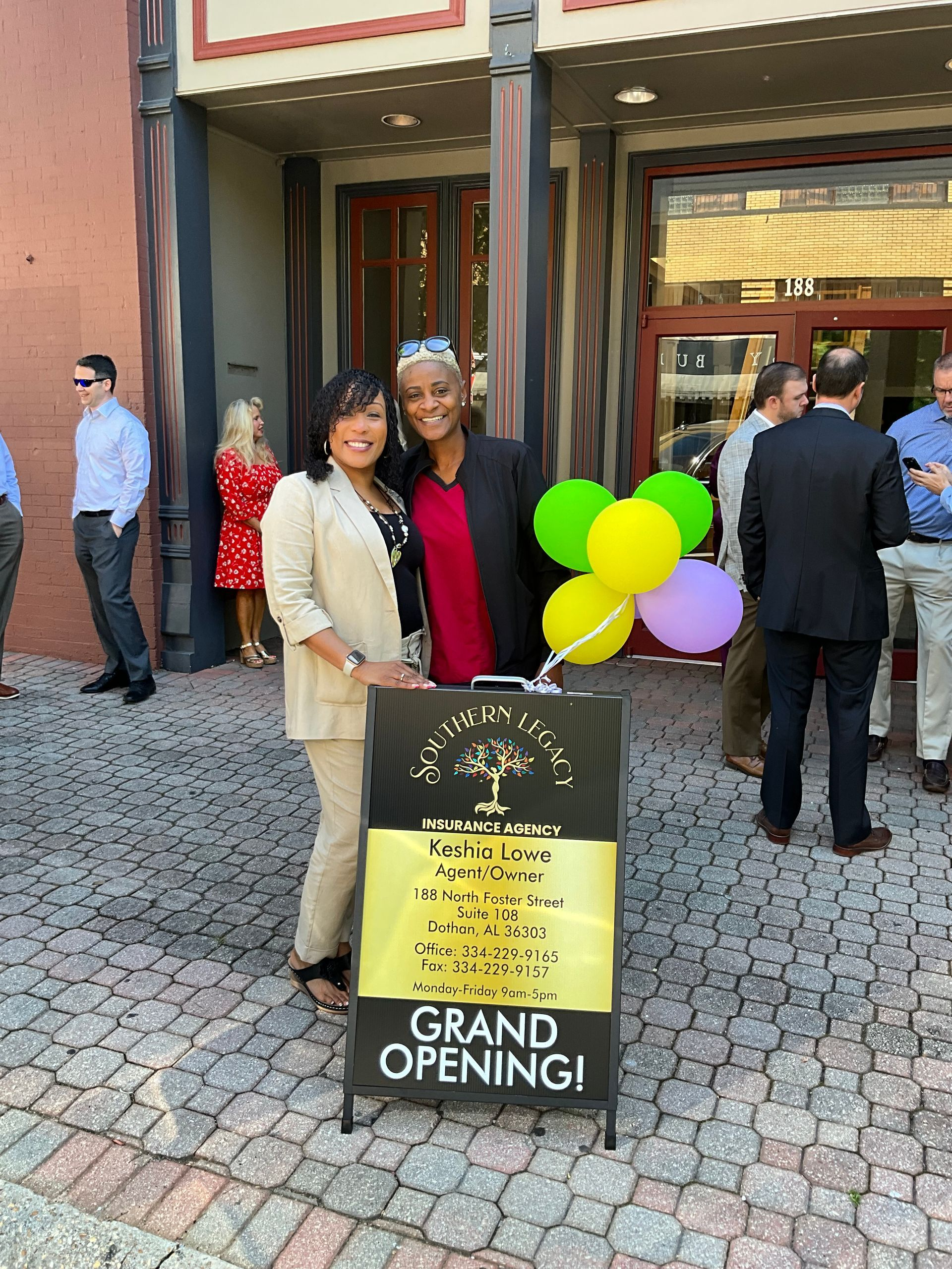 Two women are standing next to a sign that says grand opening.