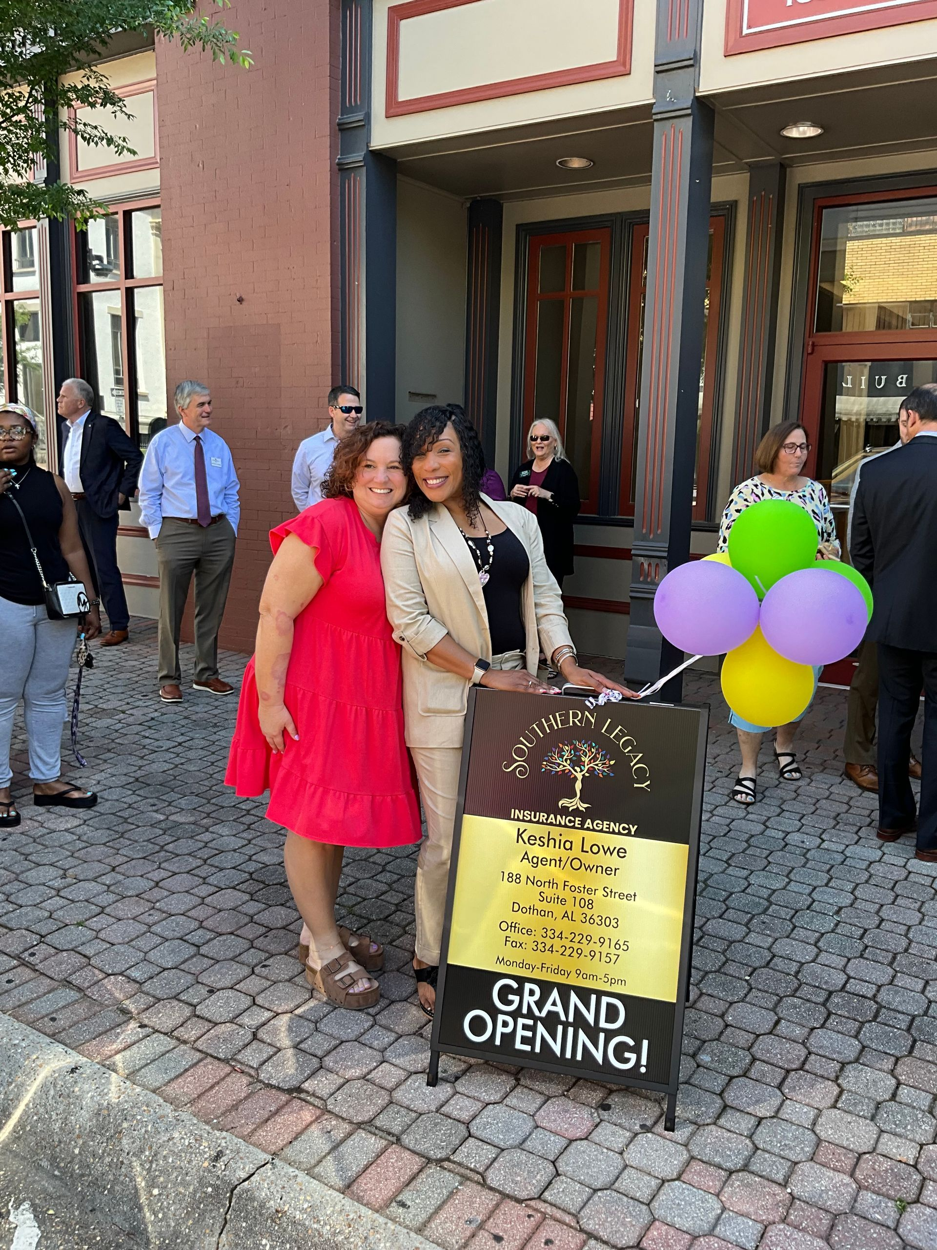Two women are standing next to a sign that says grand opening.