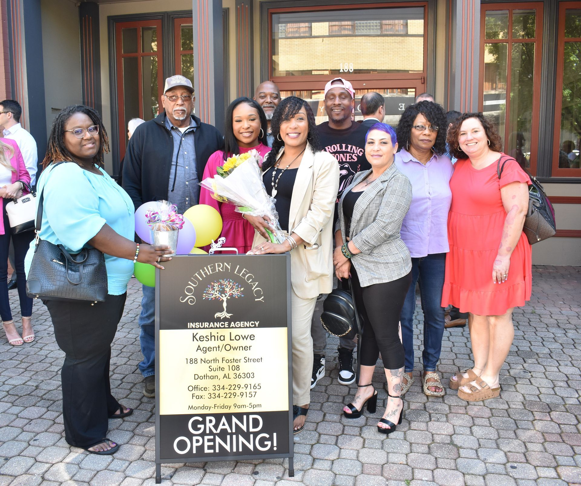 A group of people standing in front of a sign that says grand opening