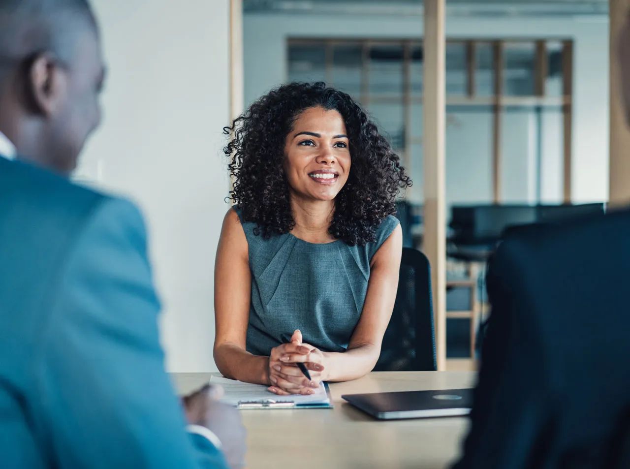 A woman is sitting at a table talking to two men.