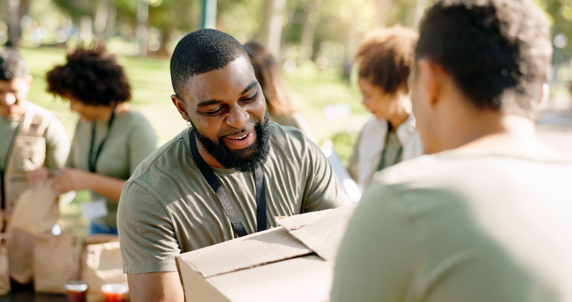 A man is holding a cardboard box and talking to a woman.