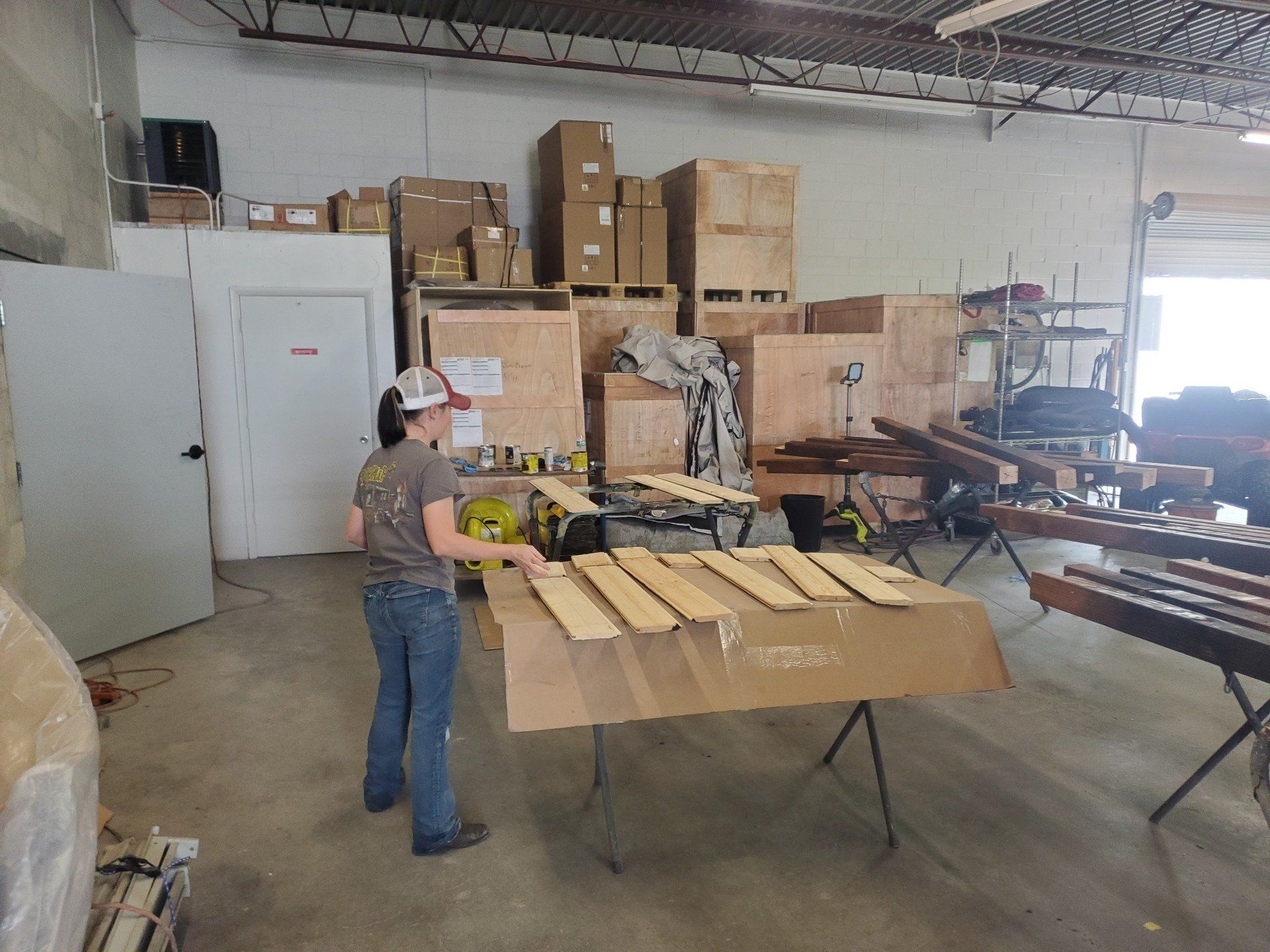 A woman is standing next to a table with wooden boards on it.