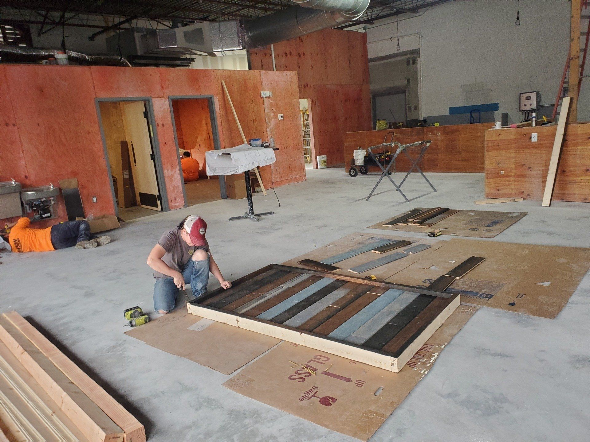 A man is working on a piece of wood in a large room