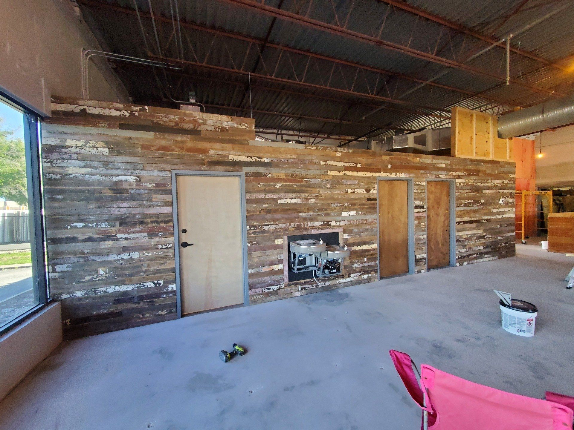 A large room with a wooden wall and a pink chair.