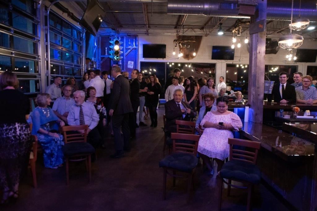 A large group of people are sitting in a room at a party.