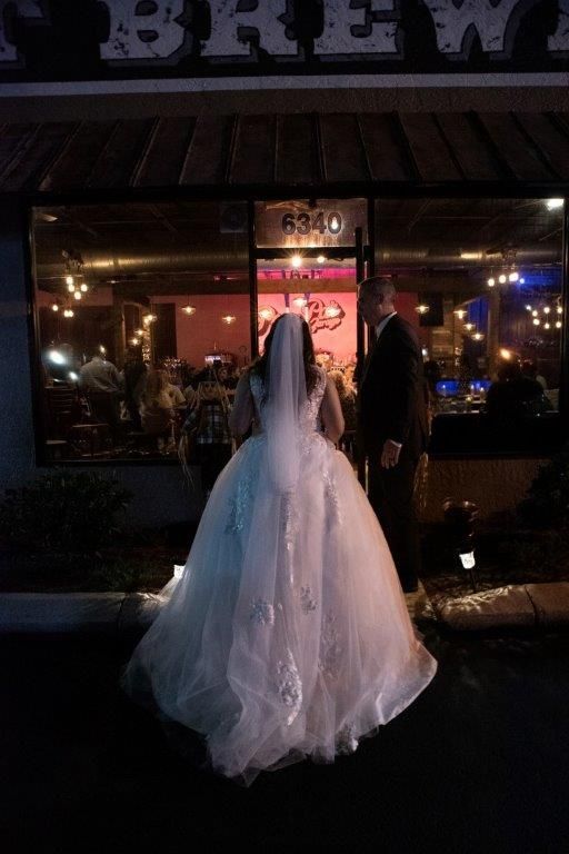 A bride and groom are standing in front of a restaurant at night.