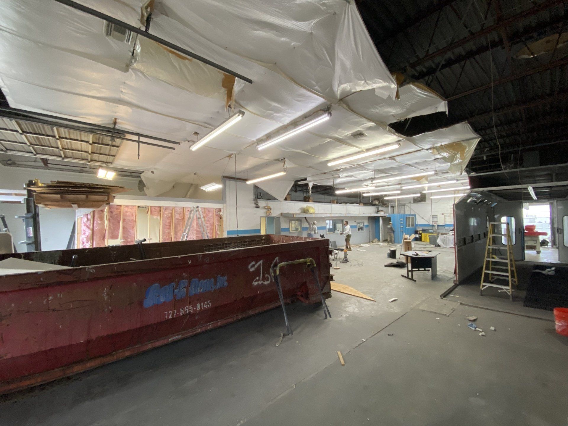 A large warehouse with a red dumpster in the middle of it.