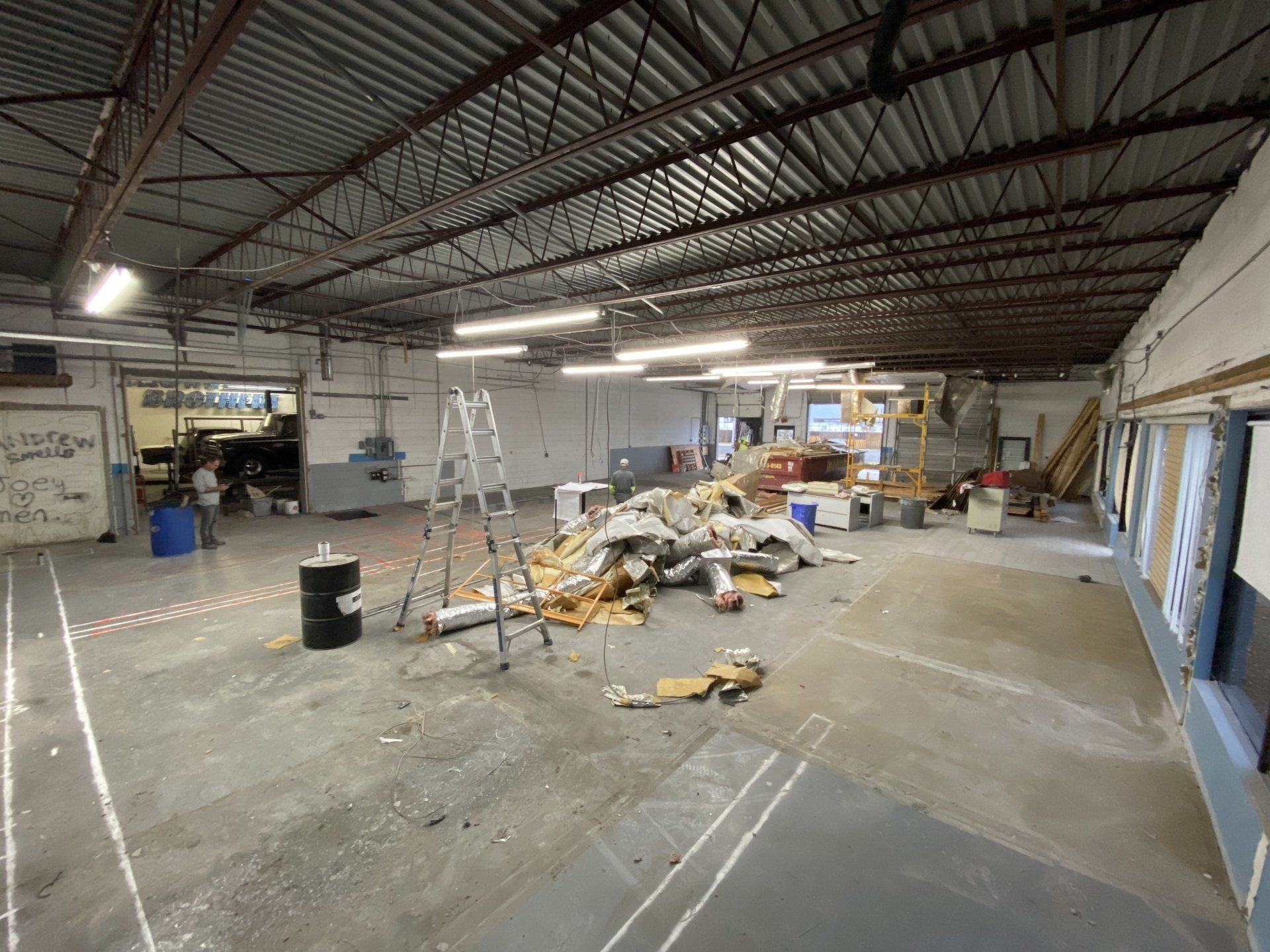 A large empty warehouse with a lot of trash on the floor.