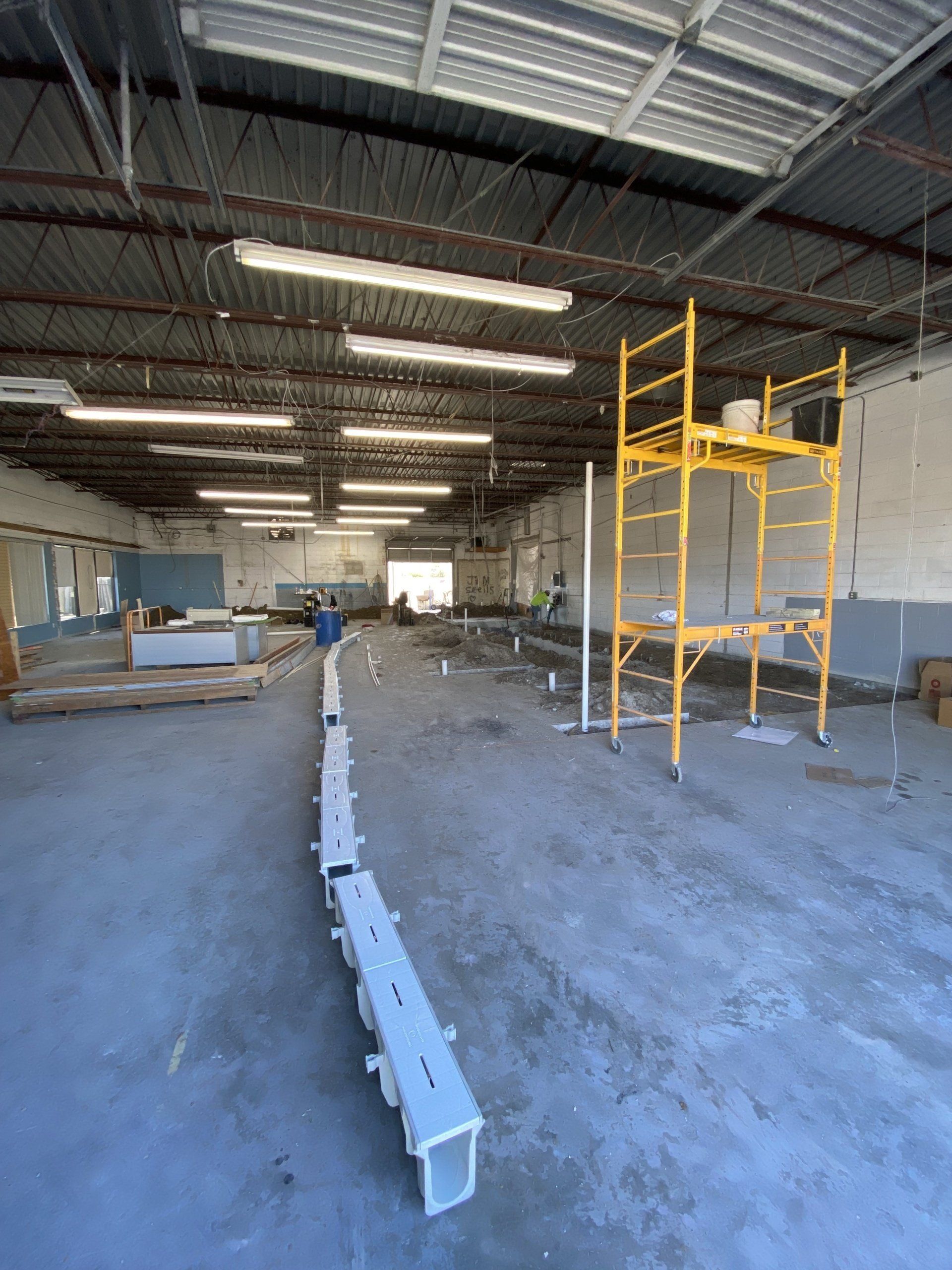A large empty warehouse with a yellow scaffolding in the middle.