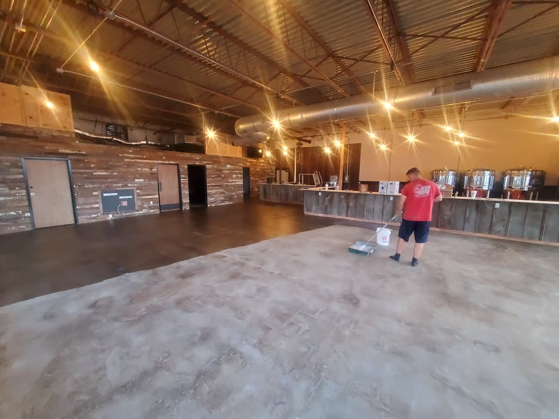 A man in a red shirt is standing in a large empty room.