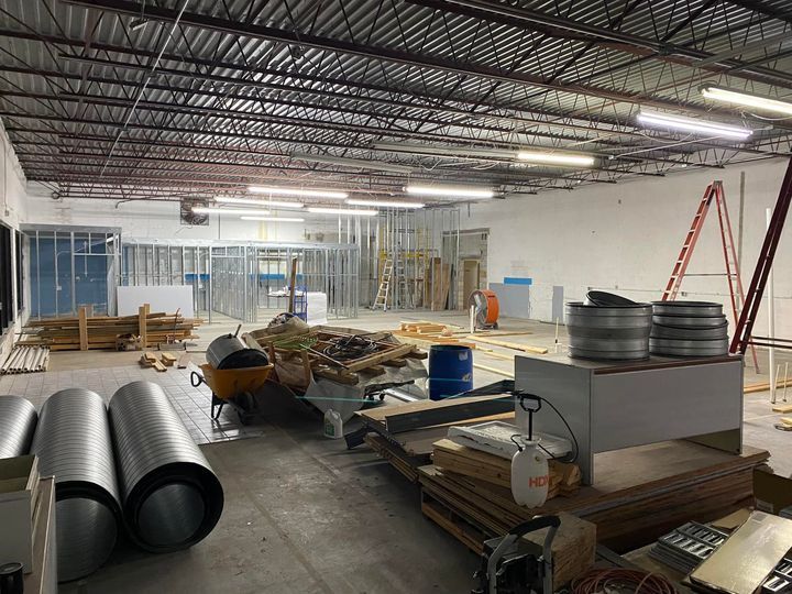 A large room with a lot of pipes and a wheelbarrow in it.