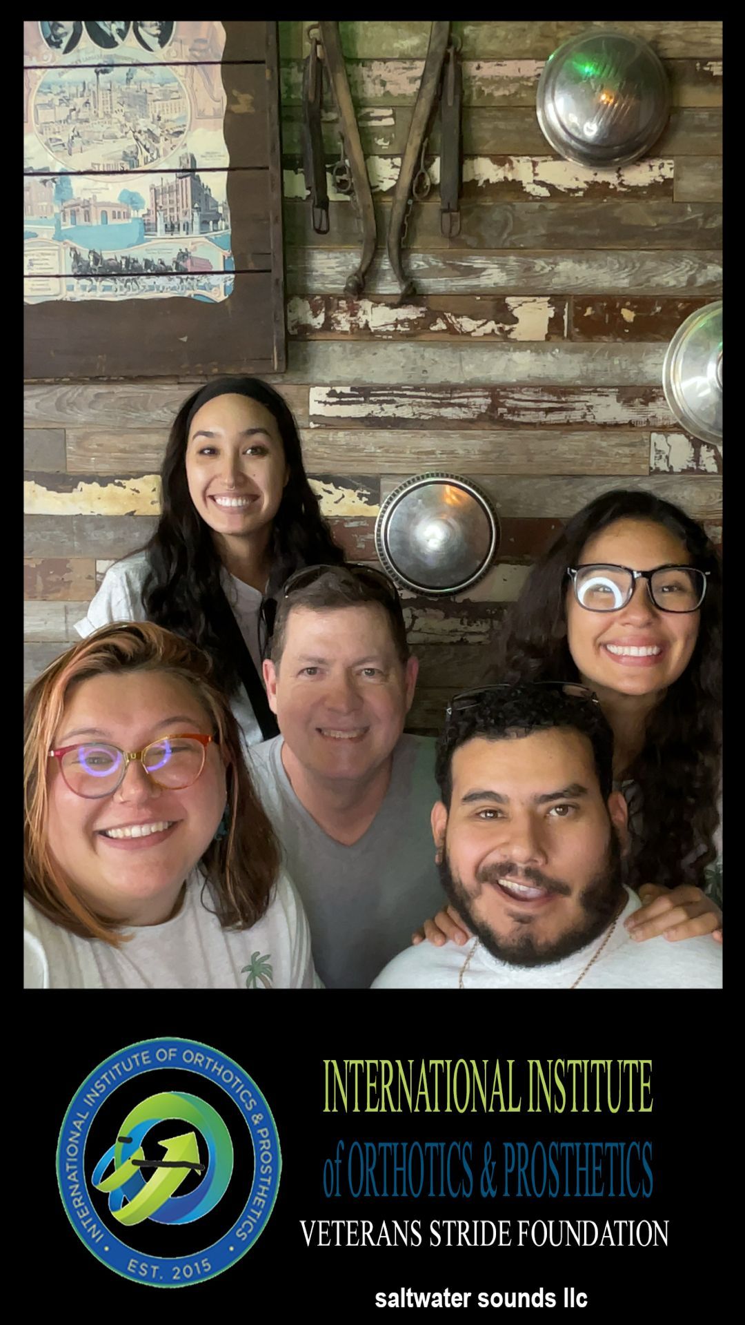 A group of people are posing for a picture in front of a wooden wall.