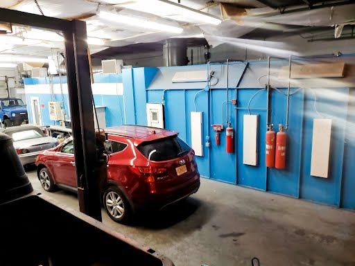 A red car is parked in a garage next to a blue wall.