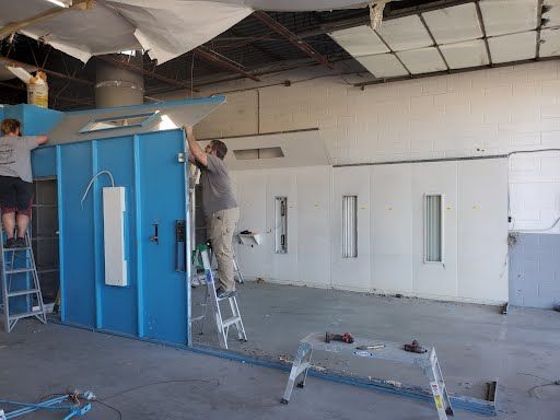 A man is standing on a ladder in front of a blue building.